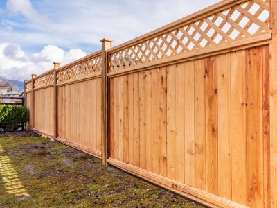 This image shows a light colored wood fence with decorative lattice on the top.